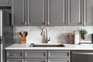 Grey kitchen with gold faucet and marble tile, grey cabinet update